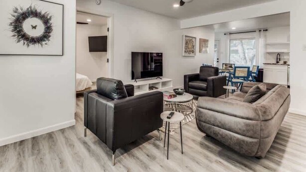 Una sala de estar moderna con una televisión de pantalla plana, dos sofás, una mesa de centro y un ventilador de techo.