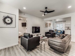 A modern living room with a flat-screen TV, two sofas, a coffee table, and a ceiling fan.
