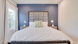 Un dormitorio con una cama grande, dos mesitas de noche y una ventana con cortinas.