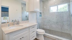 Un baño moderno con lavamanos de mármol, inodoro y ducha a ras de suelo.