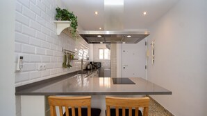 A modern kitchen with white subway tiles, stainless steel appliances, and a central island with two wooden chairs. - Ref: 278  Beach apartment with pool and parking (Fuengirola)