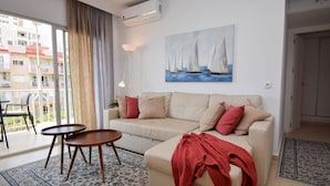 A living room with a beige sofa, two small wooden tables, a red throw blanket, and a painting of sailboats on the wall. - Ref: 278  Beach apartment with pool and parking (Fuengirola)