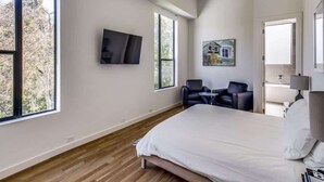 Une chambre à coucher avec un lit, une télévision, un tableau et une fenêtre.