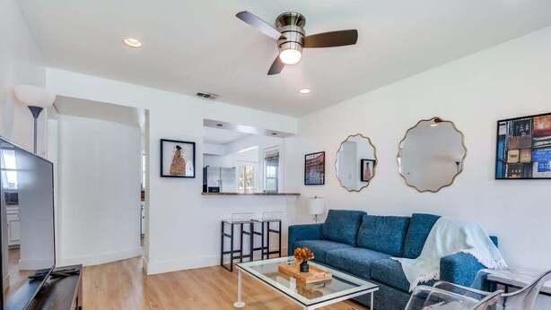 A modern living room with a sofa, coffee table, and chairs, a television, and artwork on the walls.