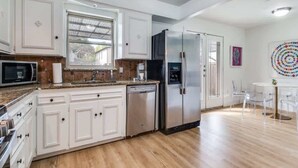 A modern kitchen with white cabinetry, stainless steel appliances, and a wooden floor.