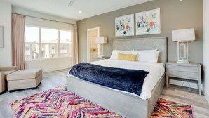 Ein modernes Hotelzimmer mit einem großen Bett, einem bunten Teppich, einem Deckenventilator und Kunstwerken an der Wand.