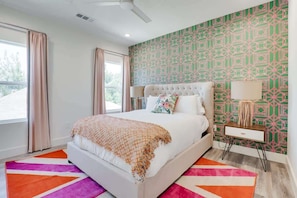 Une chambre moderne avec un lit, une table de chevet, une lampe et un mur décoré d’un motif.