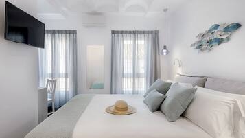 Une chambre à coucher comprenant un lit, un téléviseur fixé au mur, une fenêtre avec des rideaux et un luminaire fixé au mur.