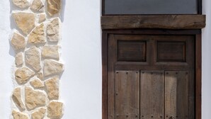 Una pared de piedra junto a una puerta de madera de diseño sencillo.