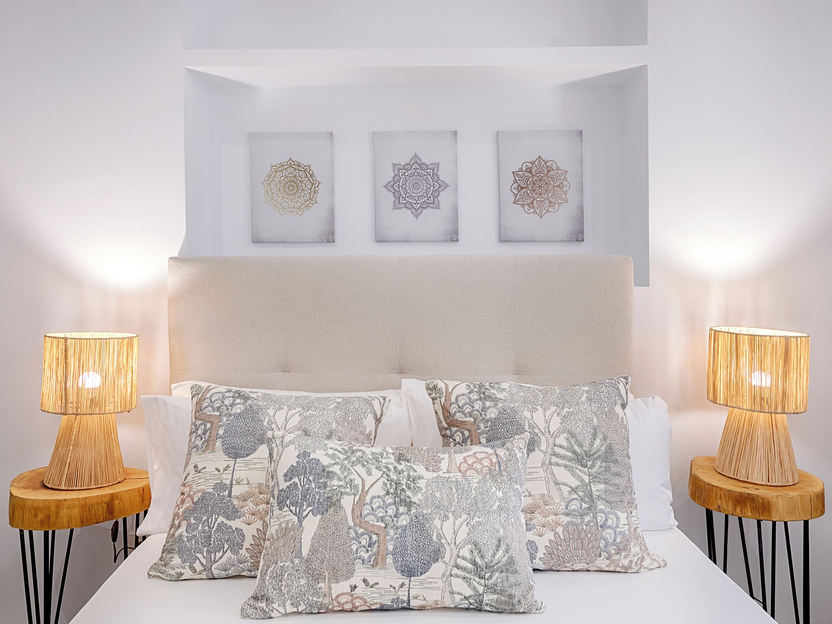 A bedroom with a bed, two bedside lamps, and three wall-mounted artworks.