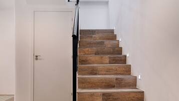 A staircase with wooden steps and a metal railing, leading to a landing with a white door.