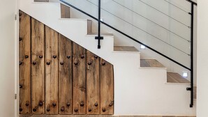 Una escalera con barandilla de vidrio, paneles de madera en un lado y un tapete estampado en la parte inferior.