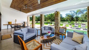 A spacious indoor area with a high ceiling, stone pillars, and a view of a lush garden.