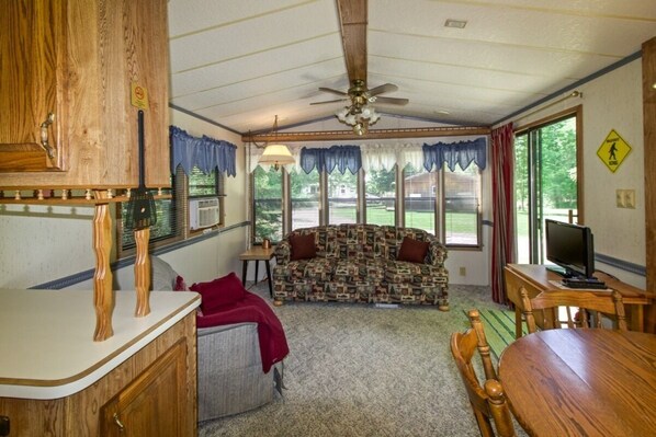 A compact living space with a kitchenette, a sofa, a television, and a dining table. - Bigfoot Bungalow at Balsam Bay Resort (Remer Township)