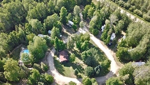 Eine Vogelperspektive eines Campingplatzes mit mehreren Wohnmobilen und Zelten, umgeben von dichtem Wald.