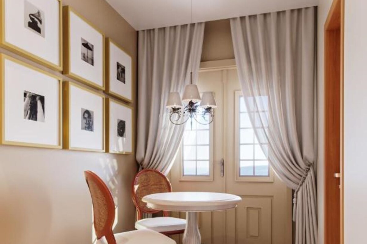 A dining area with a round table and two chairs, a chandelier, and framed pictures on the wall.