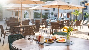 A dining table with chairs, umbrellas, and a variety of dishes and drinks. - Resende Imperial Hotel &Spa (Itacaré)