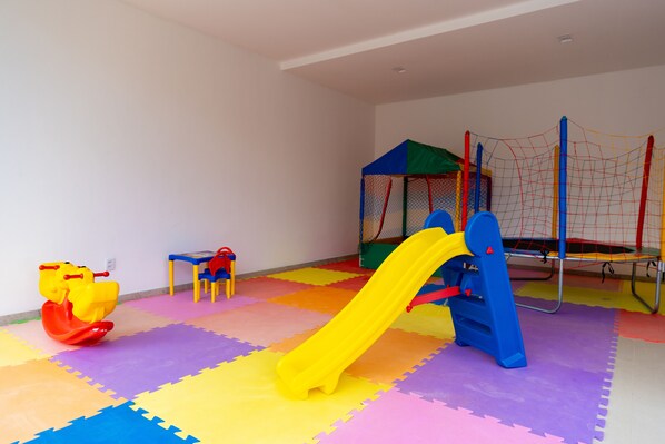 A play area with a yellow slide, a red rocking horse, and a blue climbing structure.