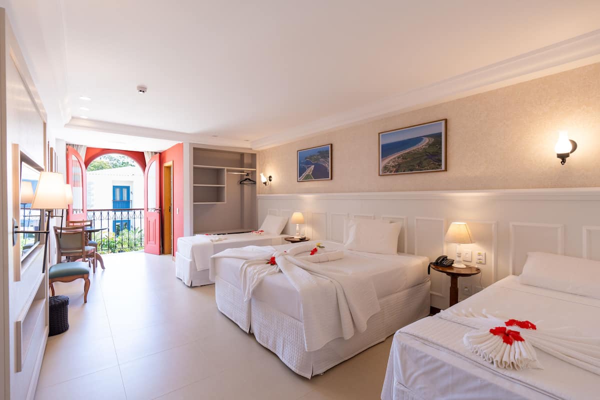 A hotel room with two beds, a balcony, and a view of the sea.