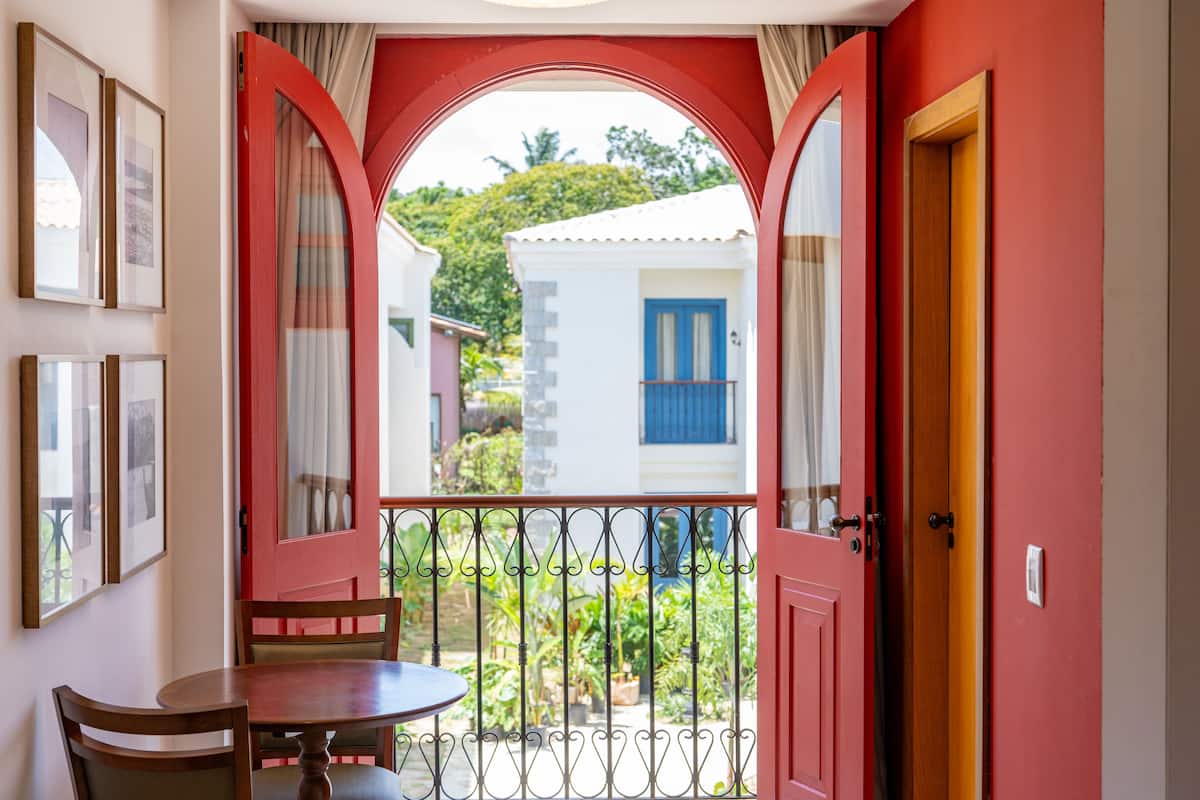 A room with a balcony, a table, and chairs.