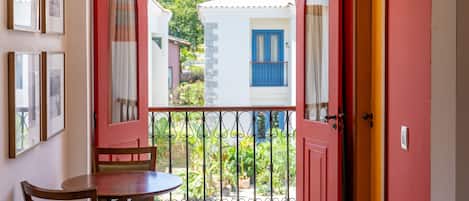 Una habitación con balcón, una mesa y sillas.