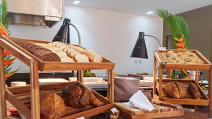 A buffet with various breads and pastries displayed on wooden stands. - Resende Imperial Hotel &Spa (Itacaré)