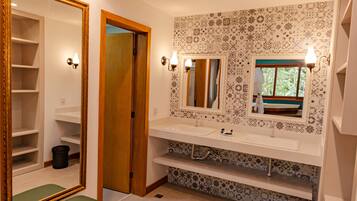 Un baño con tocador, un espejo grande, una banca y azulejos con diseño.