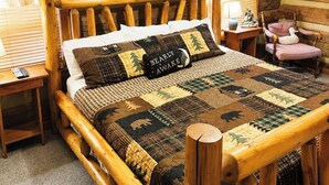 Una cama de madera rústica con colcha, un ventilador de techo y un cuadro en la pared.