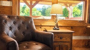 A wooden cabin interior with a leather armchair, a lamp, and a window with a view of trees. - 4 Br-Minutes to National Park!Enjoy the Farm Life! (Cosby)