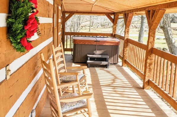 Una terraza de madera con un jacuzzi, sillas de madera y una guirnalda navideña.