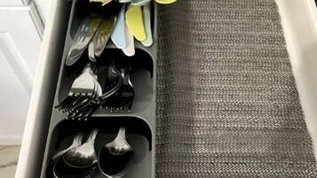 Un cajón con utensilios de cocina, incluyendo tenedores, cucharas y un rallador.