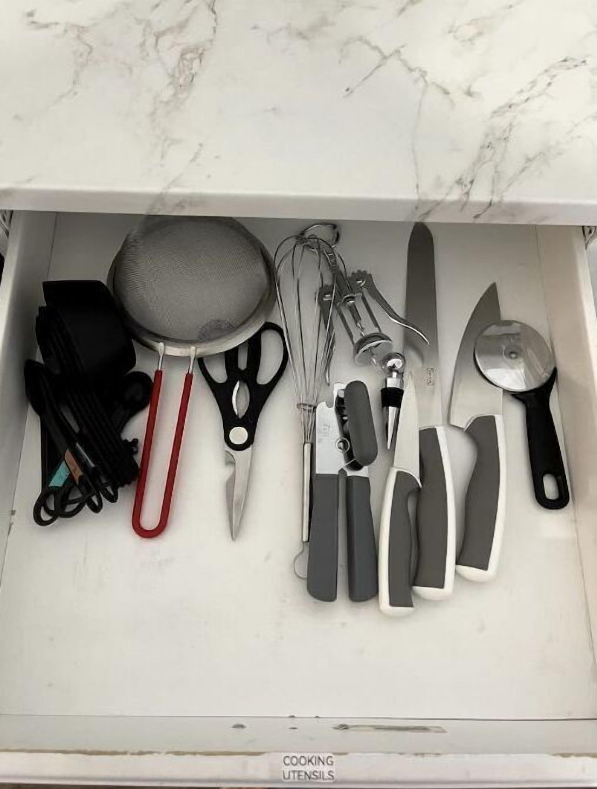 A drawer containing various cooking utensils including a strainer, scissors, and knives.