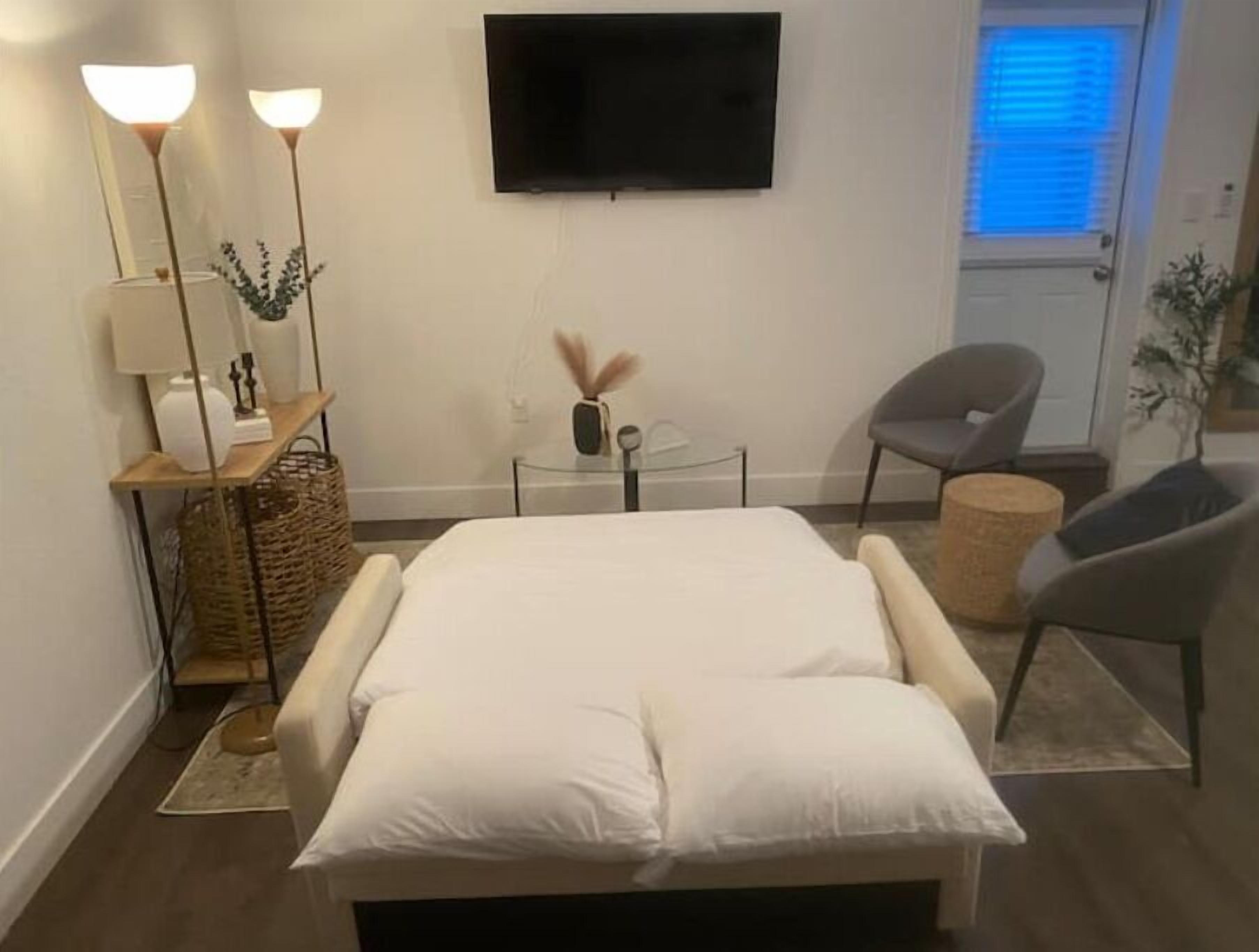 Ein modernes Schlafzimmer mit Bett, Nachttischen, Fernseher und Stuhl.
