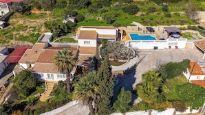 An aerial view of a residential area with multiple houses, a swimming pool, and surrounding greenery. - Casa da Saudade - Heated swimming pool, walking distance to town and beach (Carvoeiro)