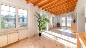 A spacious room with large windows, wooden ceiling beams, and a potted plant. - Casa da Saudade - Heated swimming pool, walking distance to town and beach (Carvoeiro)