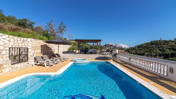 A swimming pool with a dolphin design, stone walls, lounge chairs, and a pergola. - Casa da Saudade - Heated swimming pool, walking distance to town and beach (Carvoeiro)