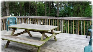 Eine Holzterrasse mit Picknicktisch und Stühlen.