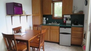 A compact kitchen with wooden cabinets, a sink, a microwave, and a small refrigerator. - 1 bedroom Cottage with unobstructed views of Otsego Lake (Cooperstown)