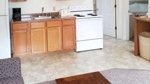 A compact kitchen with wooden cabinets, a white stove, and a countertop.