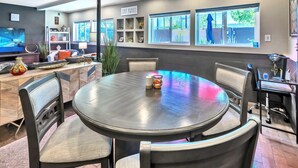 Un espace repas moderne avec une table ronde, des chaises et un téléviseur en arrière-plan.