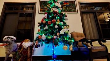 Árvore de Natal decorada com enfeites e luzes, um brinquedo de pelúcia e um cobertor no chão.