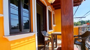 Un espace extérieur abrité, doté d’un sol carrelé, d’une table en bois et de chaises.