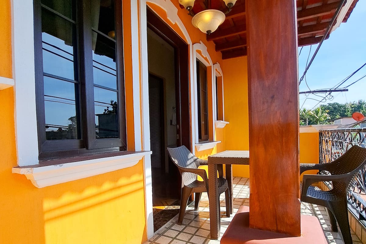 Un espacio al aire libre techado con piso de baldosas, una mesa de madera y sillas.