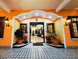 Entrada de hotel com piso de azulejos, árvore de Natal e plantas em vasos.