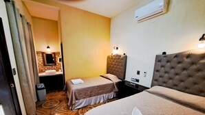 Une chambre d’hôtel avec deux lits, une salle de bain avec un lavabo et un sol à motifs.