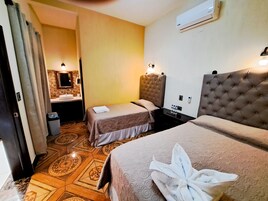 Quarto de hotel com duas camas, banheiro com pia e piso estampado.