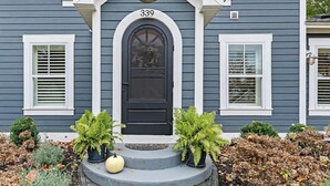 A house with a black front door, number 339, and a small porch with potted plants and a pumpkin.