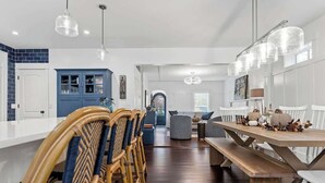 A modern kitchen with a central island, blue cabinets, and a dining area with white chairs and a wooden table.