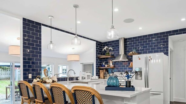 A modern kitchen with a central island, white cabinetry, and blue-tiled backsplash.