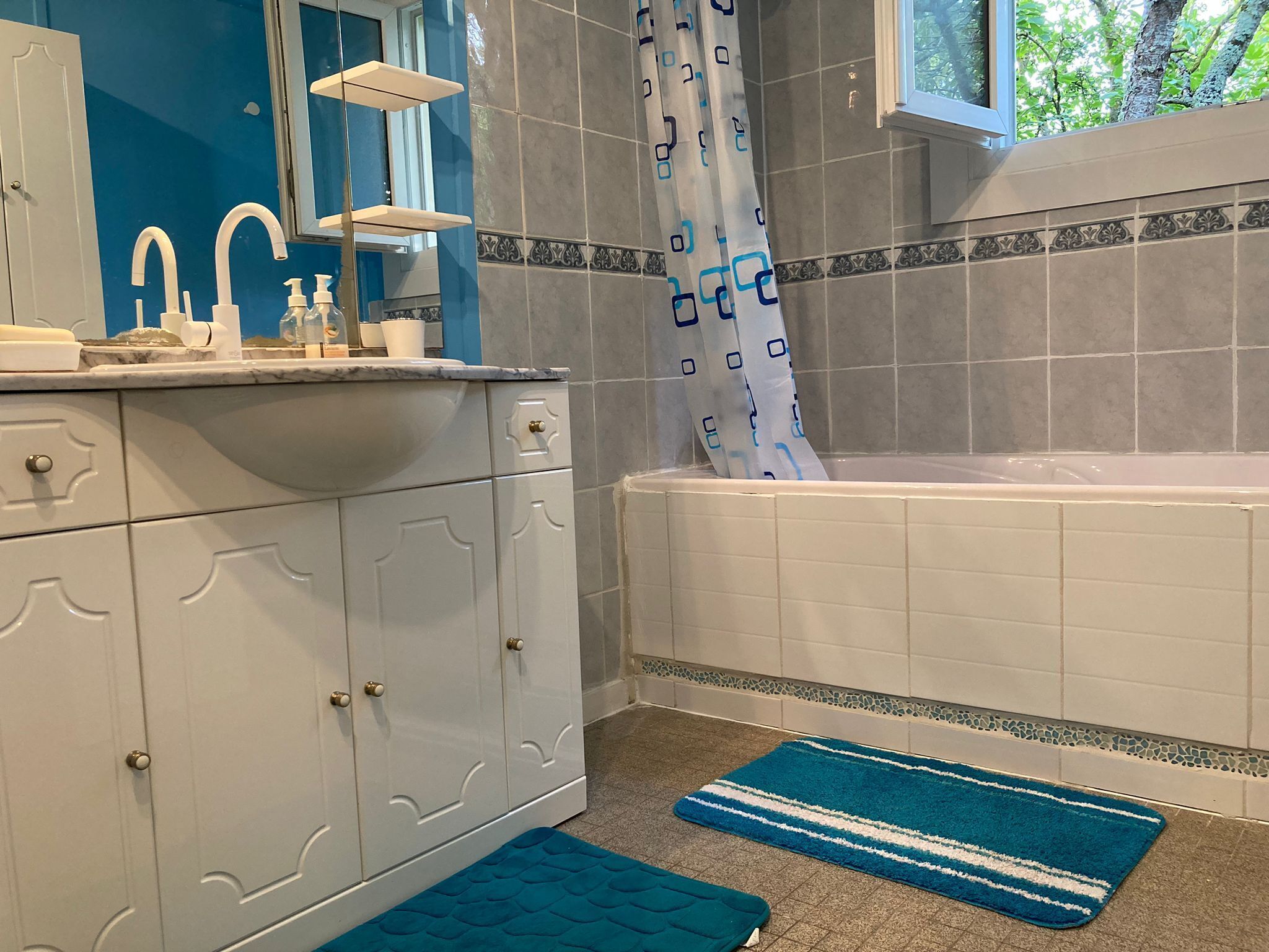 Un baño con tocador blanco, bañera y cortina de ducha.